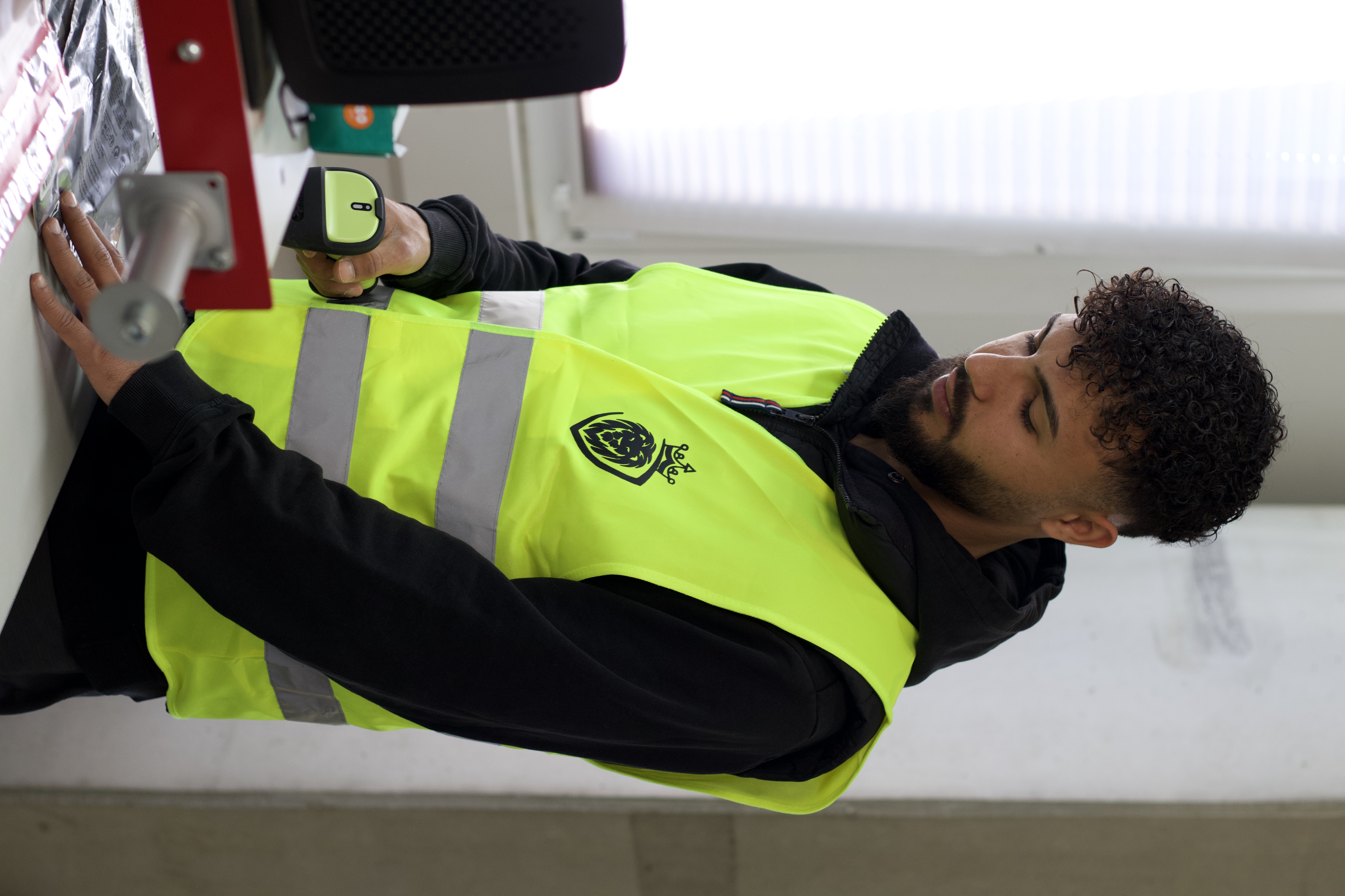 Mitarbeiter scannt Ware an Packstation im Lager mit gelber Warnweste