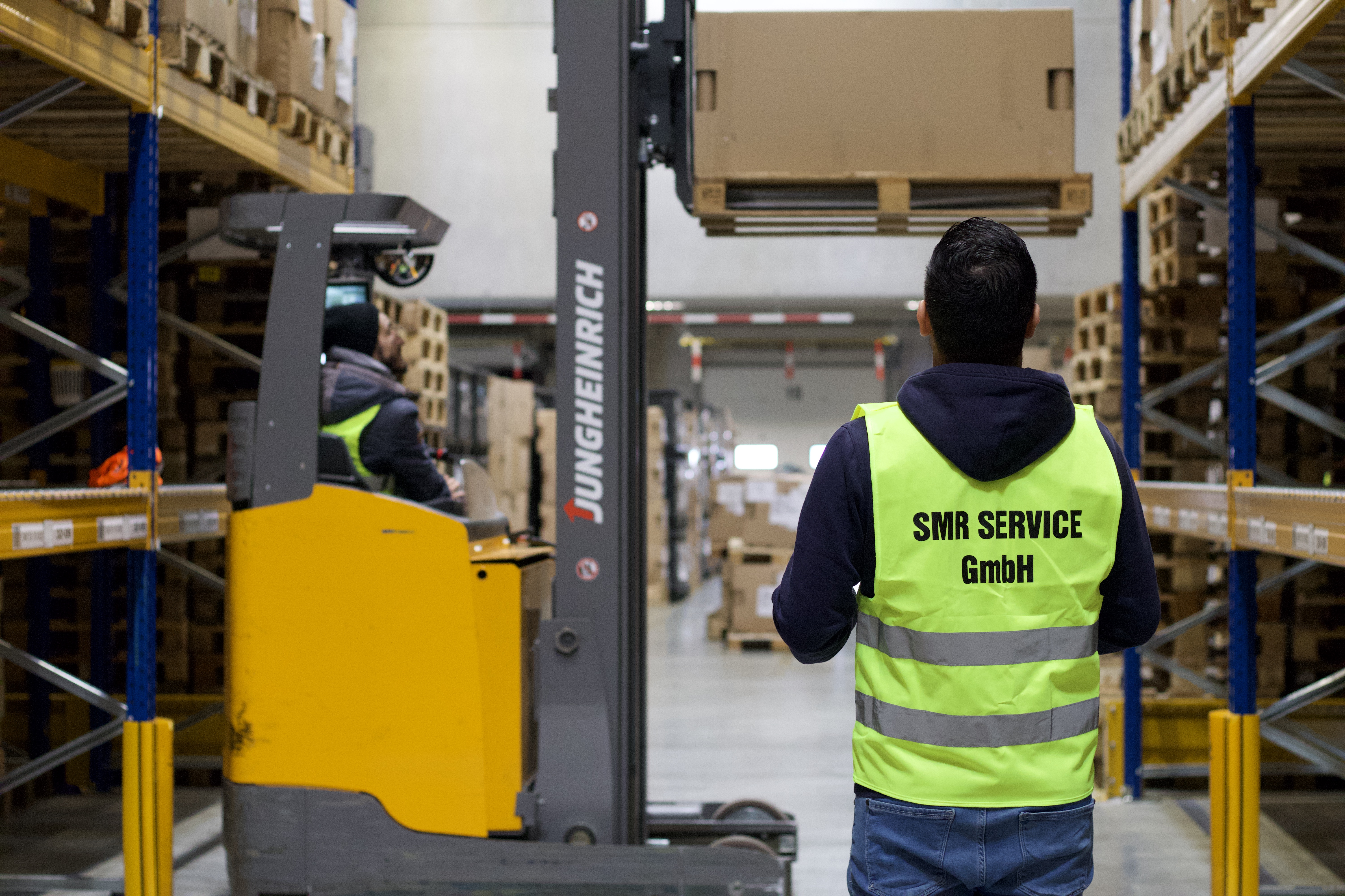Teamarbeit im Lager mit Jungheinrich Stapler und SMR Service GmbH Mitarbeitern